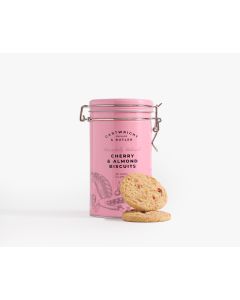 A pink tin with a metal clasp of Cartwright & Butler cherry & almond biscuits with illustrations of a piece of pie in front of the tin is two biscuits 