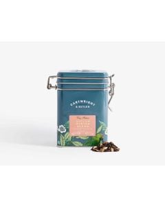 Dark blue tin with metal clasp of Cartwright & Butler Spiced winter blend tea with colourful illustrations of flowers, leaves, and a bird. With a small amount of tea blend placed in front of the tin 