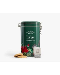 Dark green tin with metal clasp of Cartwright & Butler afternoon tea & biscuit selection with colourful illustrations of leaves, flowers, a bird, and a clock. In front of the tin is two biscuits and two tea bags 