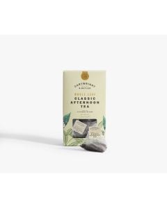 Light green box with small clear window of Cartwright & Butler classic afternoon tea with illustrations of leaves in green. In front of the box is a tea bag