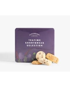 Dark purple metal tin of Cartwright & Butler teatime shortbread selection with different illustrations of flowers in reds, greens, and purples. In front of the tin is four different shortbreads
