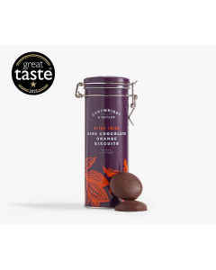 Dark purple tin with metal clasp of Cartwright & Butler ultra thick dark chocolate orange biscuits with illustrations of plants in orange, in front of the tin is two chocolate biscuits 